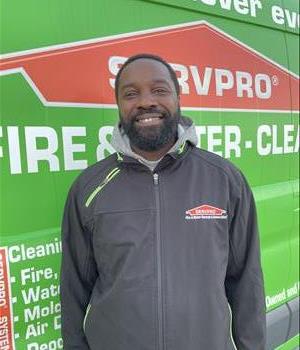 Male SERVPRO employee in uniform standing against service truck